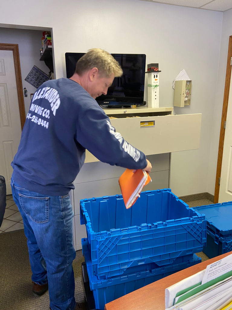 Mover organizing items into storage bins during residential moving and packing service in Ohio